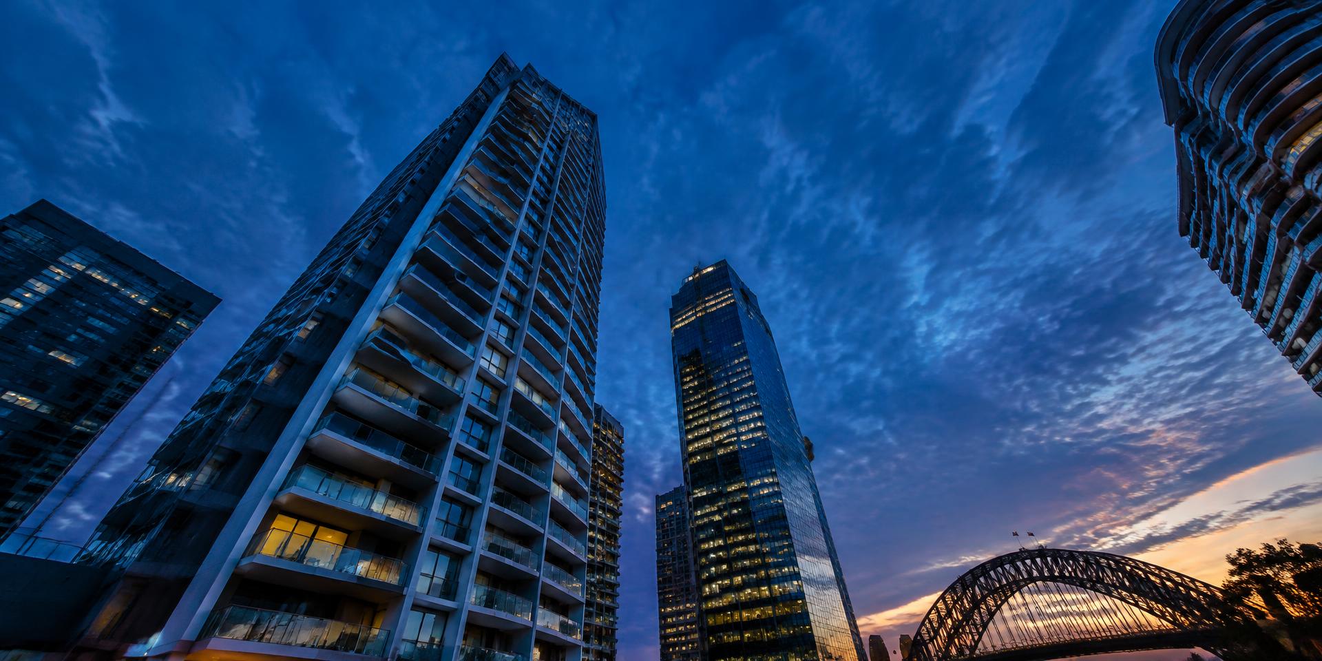Looking up at high-rise apartment and office towers in Sydney at dusk