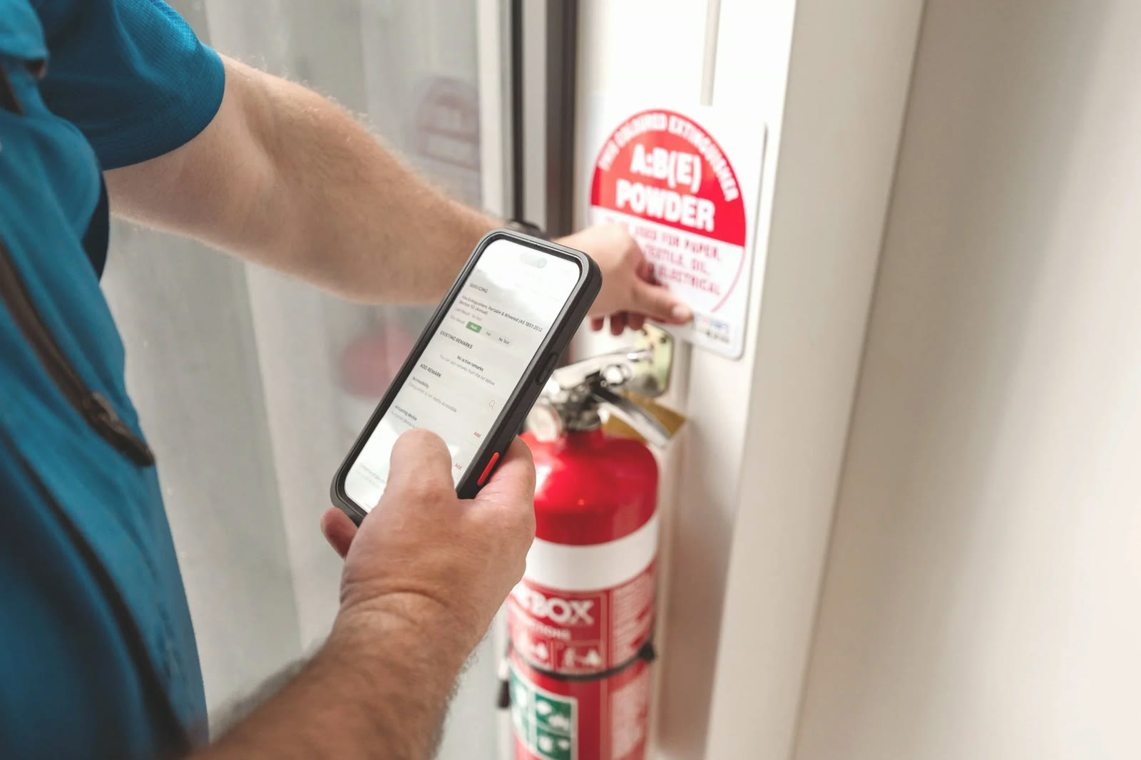 Cowan Fire technician recording an extinguisher inspection on a mobile device